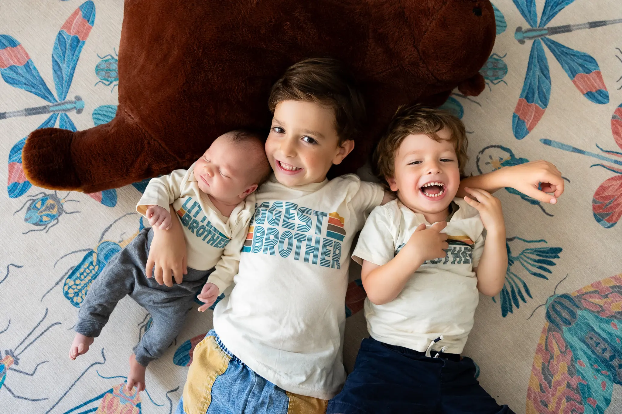 Brothers laying on floor with newborn brother