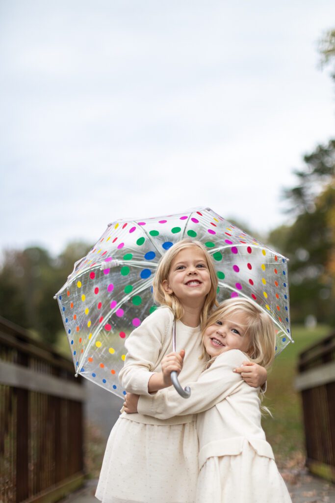 two sisters laughing under an umbrella in Mabry Park
