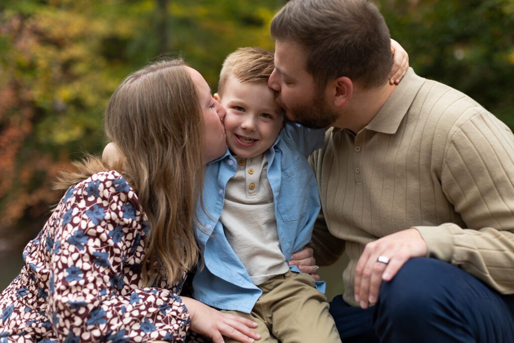 mom and dad hug and kiss boy on cheek in Roswell