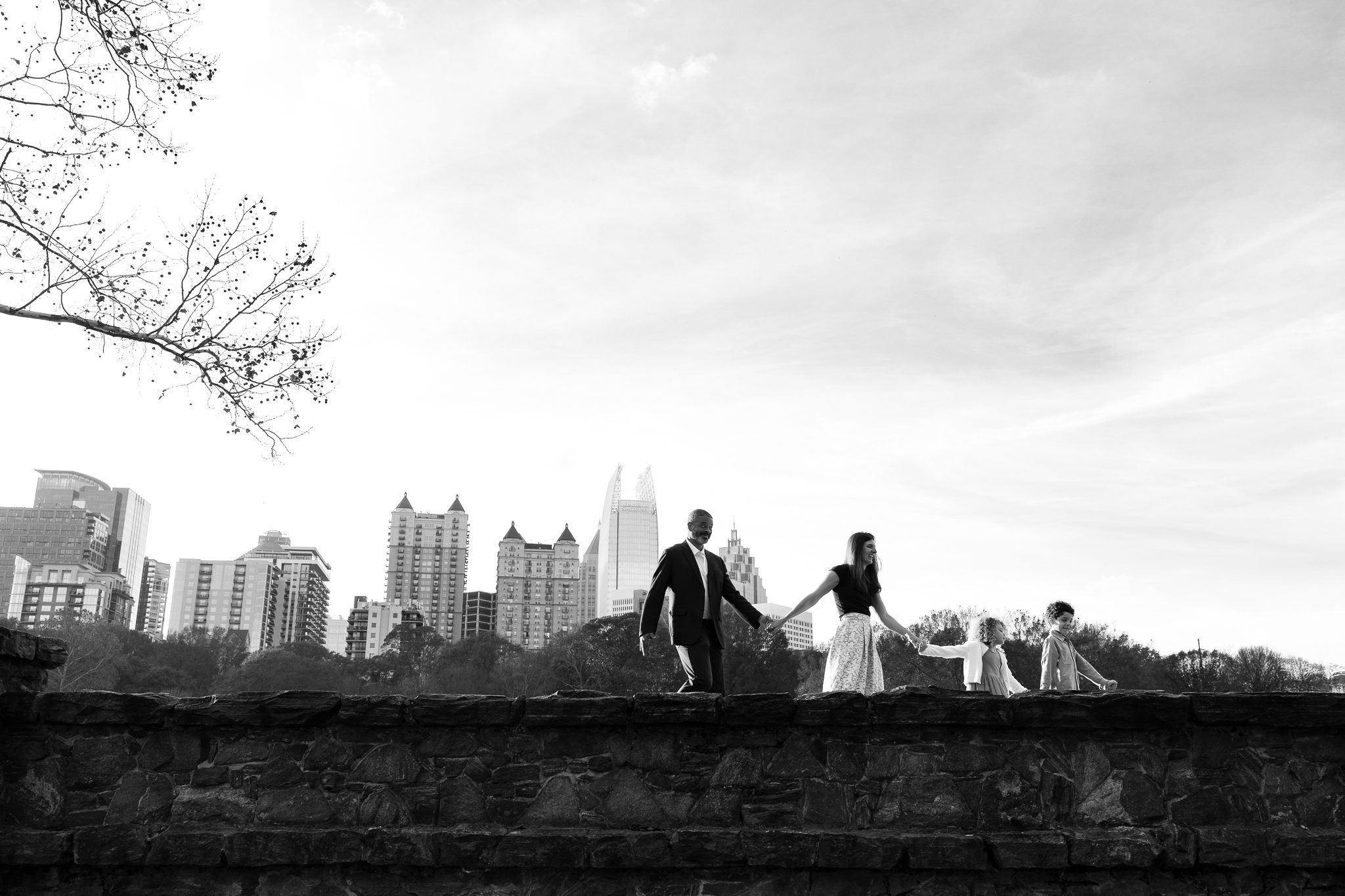 Family walking on wall across Atlanta skyline in Piedmont Park