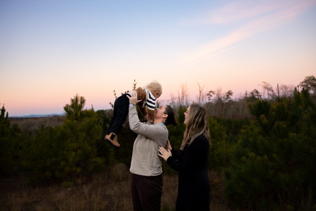 parents lifting toddler into the air during sunset family photography session in Canton